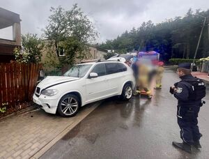 Rozbite BMW stoi przy ogrodzeniu, w które uderzyło, jest to drewniany płot, przy tym pojeździe stoi policjant. Na kolejnym zdjęciu widoczne jest suzuki, które zostało uszkodzone przez bmw