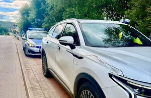 Policjanci pracują na miejscu wypadków, na zdjęciu widoczny jest niebieski samochód z rozbitym przodem, motocykl, rowerzysta przejeżdżający przed maską samochodu oraz radiowóz postawiony za białym samochodem oraz w innym miejscu radiowóz stojący przy chodniku.