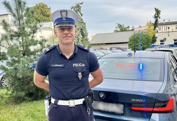 Policjant stoi przy radiowozie