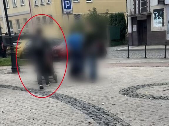 Na zdjęciu widać rozmycie na sylwetce osoby, która prowadzi wózek dziecięcy i obok niej idą dwie inne osoby